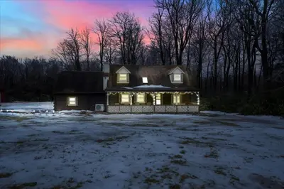 a house with lights on in a field with snow at Cabin in Long Pond Gameroom Pool Table in Long Pond