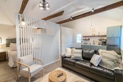a living room with a black leather couch and a bedroom at AmishGuestCottage~cozystudio~hottub~patio in Gordonville