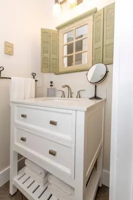 a white bathroom with a sink and a mirror at AmishGuestCottage~cozystudio~hottub~patio in Gordonville