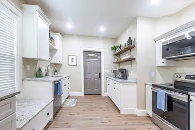 a kitchen with white cabinets and a wooden floor at The Queen Place - Updated-Private Backyard in Gordonville