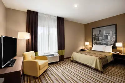 a hotel room with a bed and a chair and a television at Super 8 by Wyndham Hershey Chocolate Avenue in Hershey