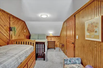 a bedroom with a bed and wooden walls at Log Cabin and Guest House Sleeps 18 2 Game Rooms in Long Pond