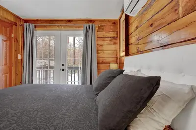 a bedroom with a bed and a large window at Log Cabin and Guest House Sleeps 18 2 Game Rooms in Long Pond
