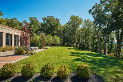 a large grassy yard with trees and a building at Pendry Natirar in Peapack