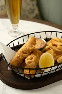 a basket of food with onion rings and fries and a drink at Pendry Natirar in Peapack