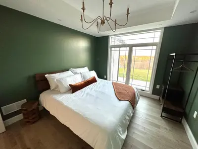 a green bedroom with a bed and a chandelier at New Farmhouse, King Beds, Game Room, Hot Tub & View! in Montgomery