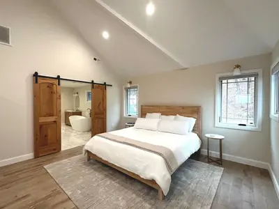 a bedroom with a large bed and a bathroom at New Farmhouse, King Beds, Game Room, Hot Tub & View! in Montgomery