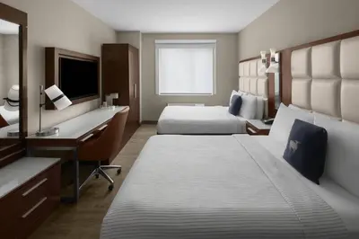 a hotel room with two beds and a desk at Cambria Hotel New York - Chelsea in New York