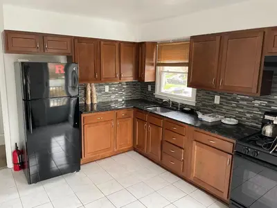 a kitchen with wooden cabinets and a black refrigerator at Cozy Home Near Downtown Rahway in Rahway