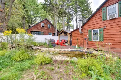 a red house with a white fence and a yard at Easy Interstate Access Original Poconos Log Cabin in Blakeslee