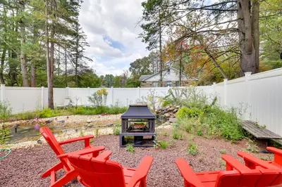 a backyard with red chairs and a fire pit at Easy Interstate Access Original Poconos Log Cabin in Blakeslee