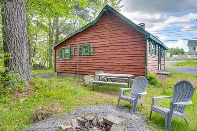a red house with two chairs and a picnic table in front of it at 4 Mi to Big Boulder The Cozy Cabin on 8 Acres! in Blakeslee