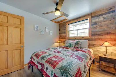 a bedroom with a bed and a wooden wall at 4 Mi to Big Boulder The Cozy Cabin on 8 Acres! in Blakeslee