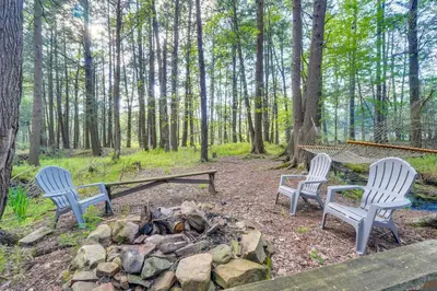 three chairs and a fire pit in the woods at Private Hot Tub Poconos Babbling Brooke Cottage in Blakeslee