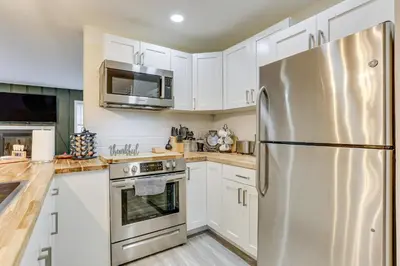 a kitchen with white cabinets and a stainless steel refrigerator at East Stroudsburg Townhouse Less Than 1 Mi to Ski Area! in East Stroudsburg