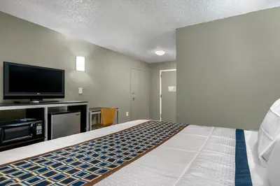a bedroom with a bed and a flat screen tv at Knights Inn Bristol in Levittown