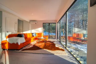 an orange couch in a living room with large windows at Brand New House with Huge Patio in Kerhonkson