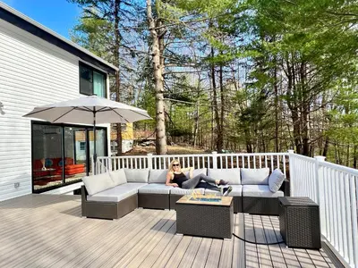 a woman sitting on a couch on a deck at Brand New House with Huge Patio in Kerhonkson