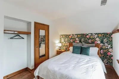 a bedroom with a white bed with a floral wallpaper at Cozy retreat in Thornton PA in Thornton