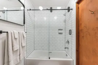 a bathroom with a tub and a shower with white tiles at Charming Studio in Thornton PA in Thornton