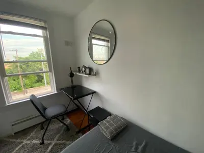 a bedroom with a mirror and a chair and a bed at Cozy apartment with city skyline. Easy commute midtown Manhattan. in Jersey City