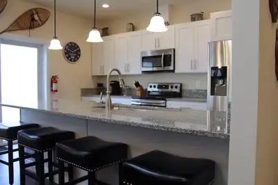 a kitchen with black bar stools and a counter top at Luxury 6 BR Rebel Ridge Retreat-Sleeps 16-Hot Tub & Linens Included in Albrightsville