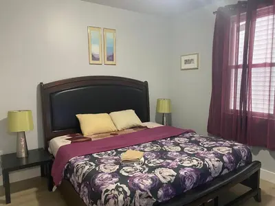 a bedroom with a bed with a purple comforter at King Suite 8Mins to Newark Airport in Newark
