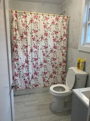a bathroom with a shower curtain with a toilet at King Suite 8Mins to Newark Airport in Newark