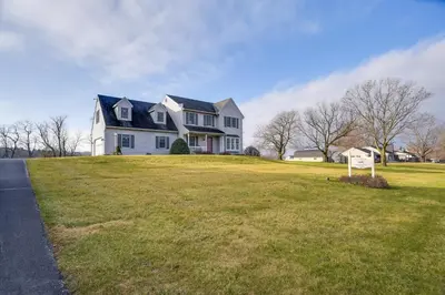 a large white house on a grassy hill at 4 Mi to the Amish Village Spacious Home with Deck! in Ronks