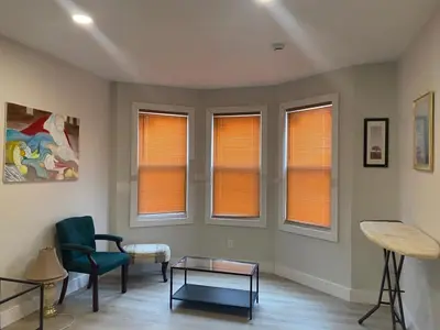 a living room with windows and a chair and a table at Stylish Room 8Mins to Newark Airport in Newark
