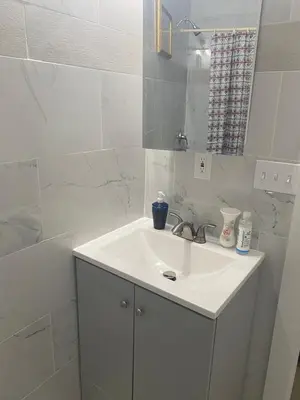 a white bathroom with a sink and a mirror at Stylish Room 8Mins to Newark Airport in Newark