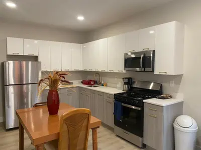 a kitchen with white cabinets and a table with a vase at Stylish Room 8Mins to Newark Airport in Newark