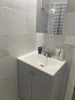 a white bathroom with a sink and a mirror at Stylish Room 8Mins to Newark Airport in Newark