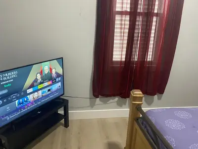 a living room with a flat screen tv next to a window at Stylish Room 8Mins to Newark Airport in Newark