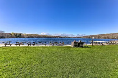 two people sitting on a bench next to a body of water at Family-Friendly Big Bass Lake Vacation Rental! in Gouldsboro