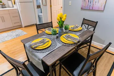 a dining room table with yellow plates and chairs at New Beautiful Apartment In Bayonne near Subway Path Train Manhattan NYC in Bayonne