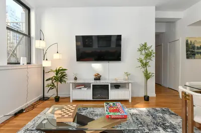 a living room with a table and a tv on the wall at Luxury 3 Bedroom Retreat in Downtown Manhattan in New York