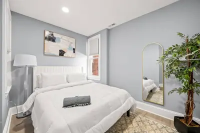 a bedroom with a large white bed and a plant at Cozy Apt in Center City! in Philadelphia