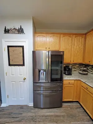 a kitchen with a stainless steel refrigerator and wooden cabinets at 5 BR Coyote Cliff Corner HUGE Luxury w/Hot Tub and Linens in Albrightsville