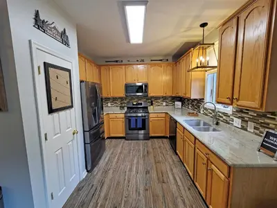 a kitchen with wooden cabinets and a stove top oven at 5 BR Coyote Cliff Corner HUGE Luxury w/Hot Tub and Linens in Albrightsville