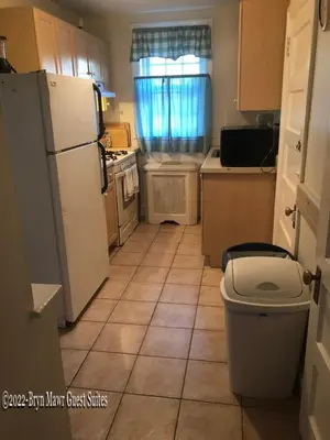a kitchen with a white refrigerator and a tile floor at Bryn Mawr Guest Suites in Bryn Mawr