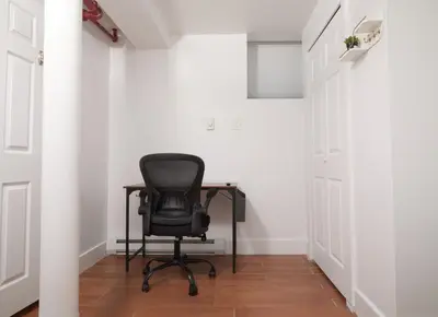 a black chair sitting in a hallway with white walls at Comfy Guest House in Hell's Kitchen in New York