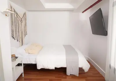 a bedroom with a bed and a tv on a wall at Comfy Guest House in Hell's Kitchen in New York