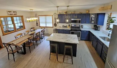a kitchen with blue cabinets and a table and chairs at Red Rock Run - Luxury 6 BR Secluded Home with Hot Tub & Linens in Albrightsville