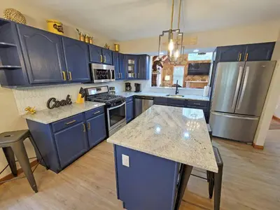 a kitchen with blue cabinets and a counter top at Red Rock Run - Luxury 6 BR Secluded Home with Hot Tub & Linens in Albrightsville
