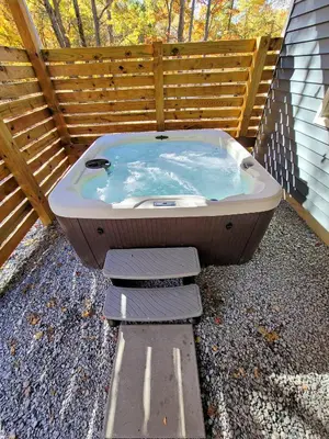 a bath tub sitting on the ground next to a fence at Timber Top Terrace - Huge Luxury 6 BR - Sleeps 16 Linens and Towels Included in Albrightsville