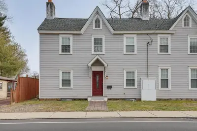 a gray house with a red door on a street at In-Town and Walkable Historic Yardley Retreat! in Yardley