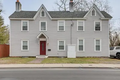 a gray house with a red door on a street at In-Town and Walkable Historic Yardley Retreat! in Yardley