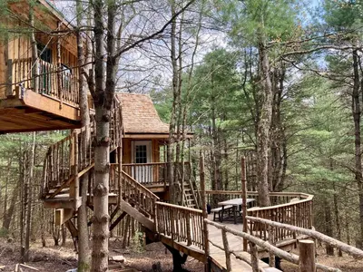 a tree house in the woods with wooden decks at Little Birds Treehouse in Sparrow Bush