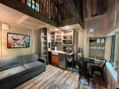 a living room with a couch and a table and a kitchen at Little Birds Treehouse in Sparrow Bush